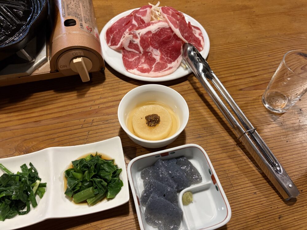 夕食の肉料理と刺身こんにゃくなどの小皿