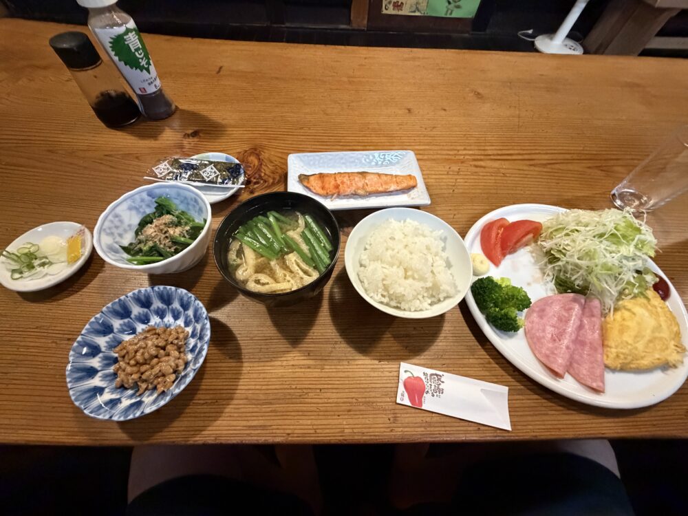 焼き魚、卵料理、野菜、ご飯などが並ぶ朝食